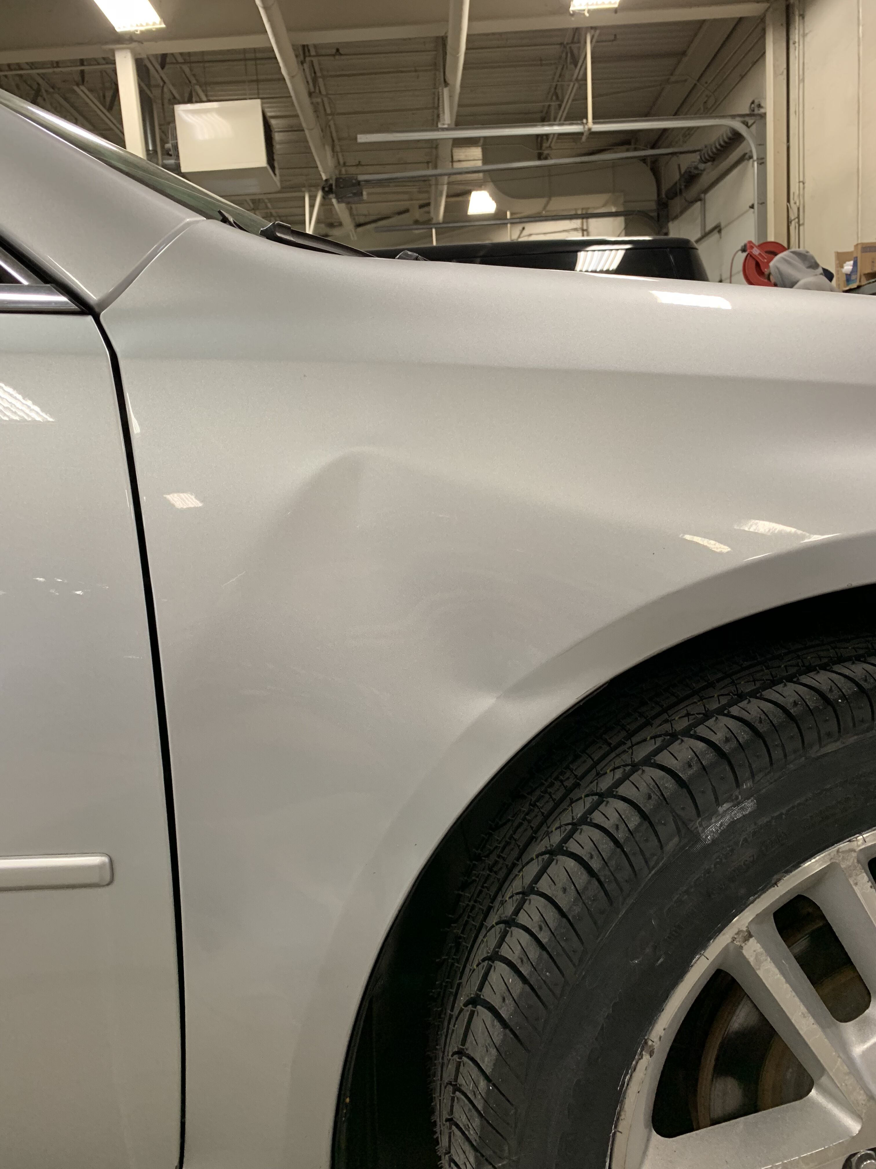 a silver car with a dent on it's front fender