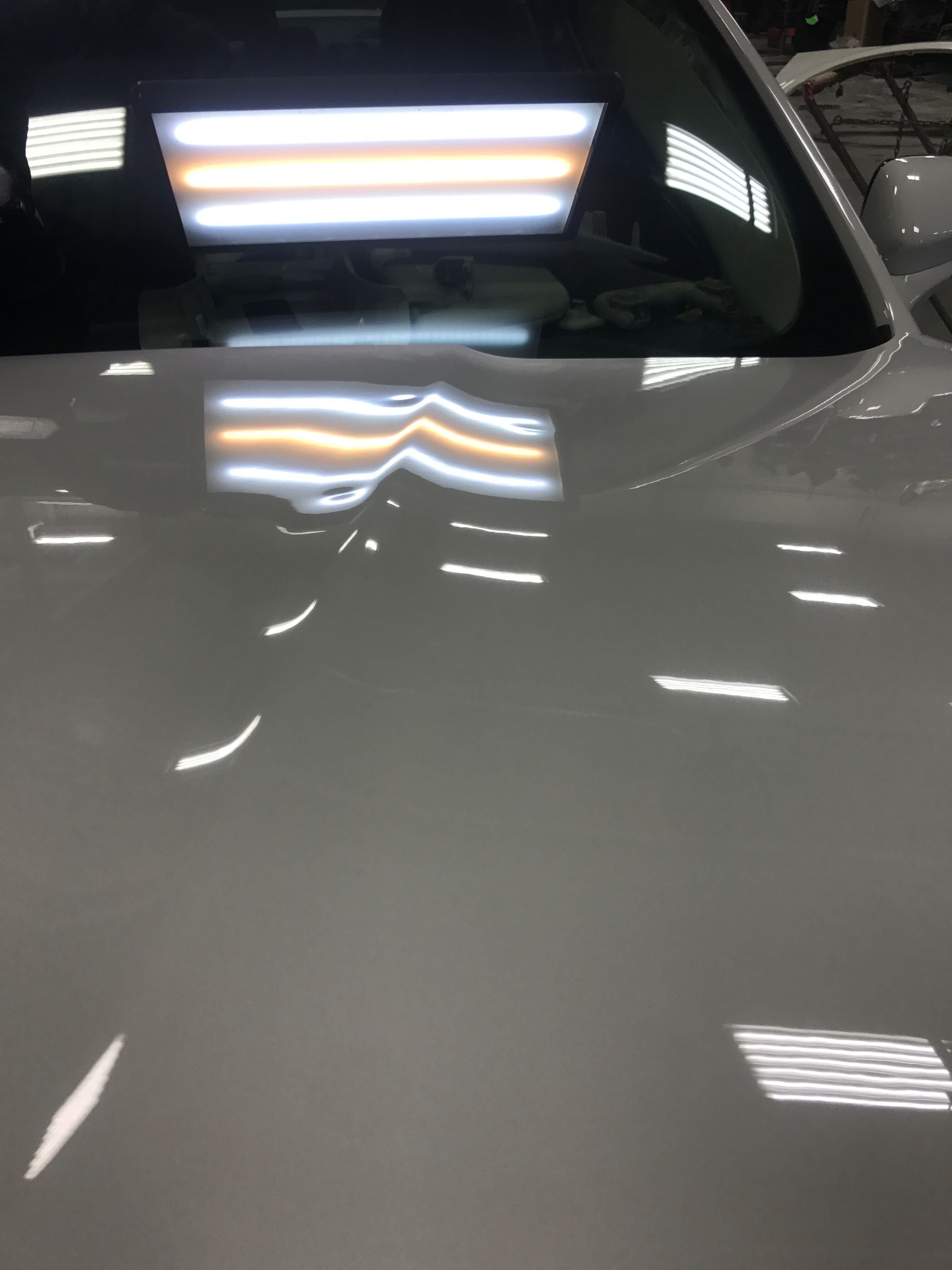 a white car with some small dents on the hood