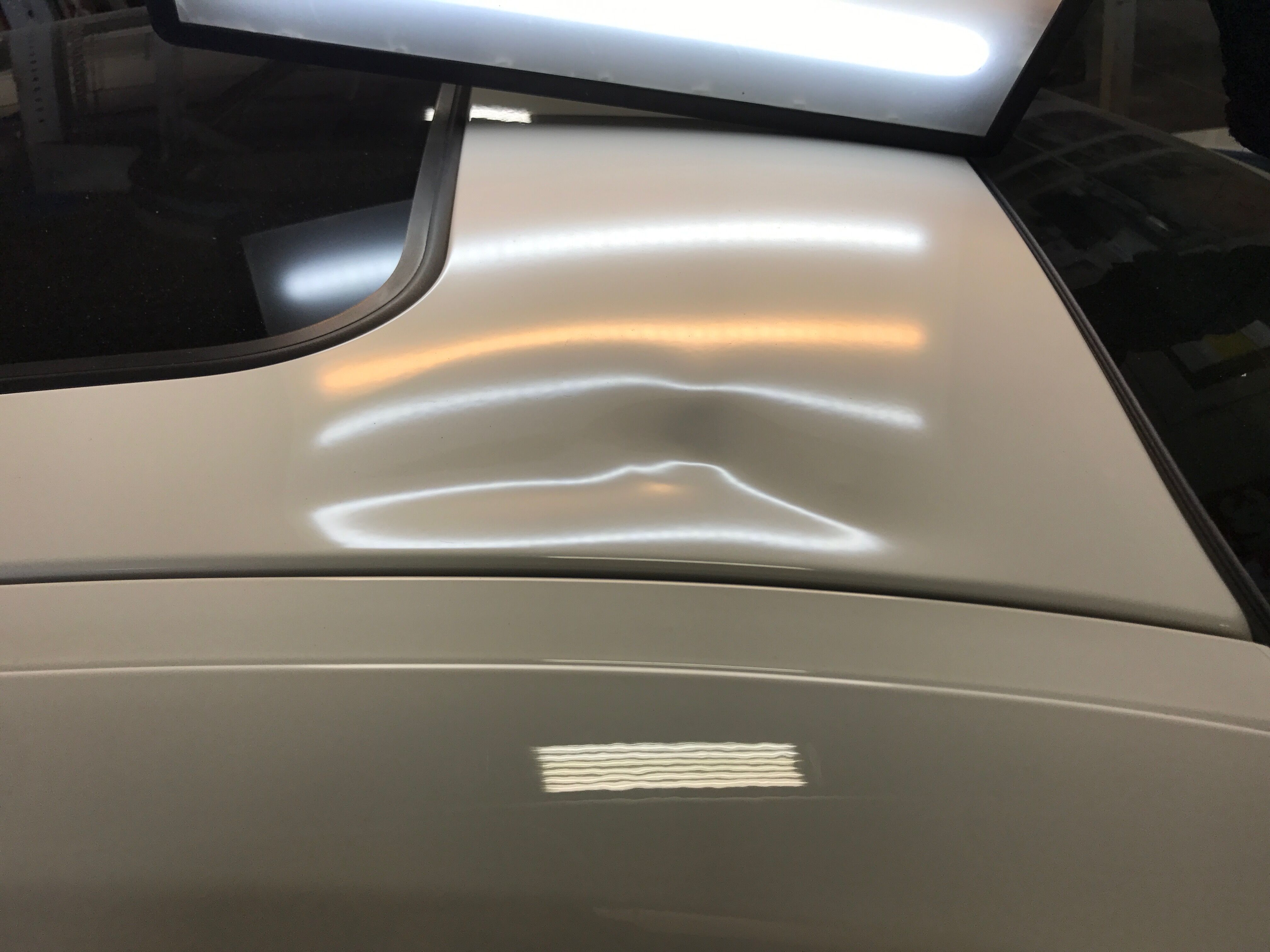 a white car with a huge dent on the roof